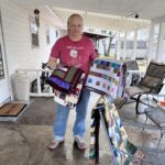 A man holding a quilt in his hand.
